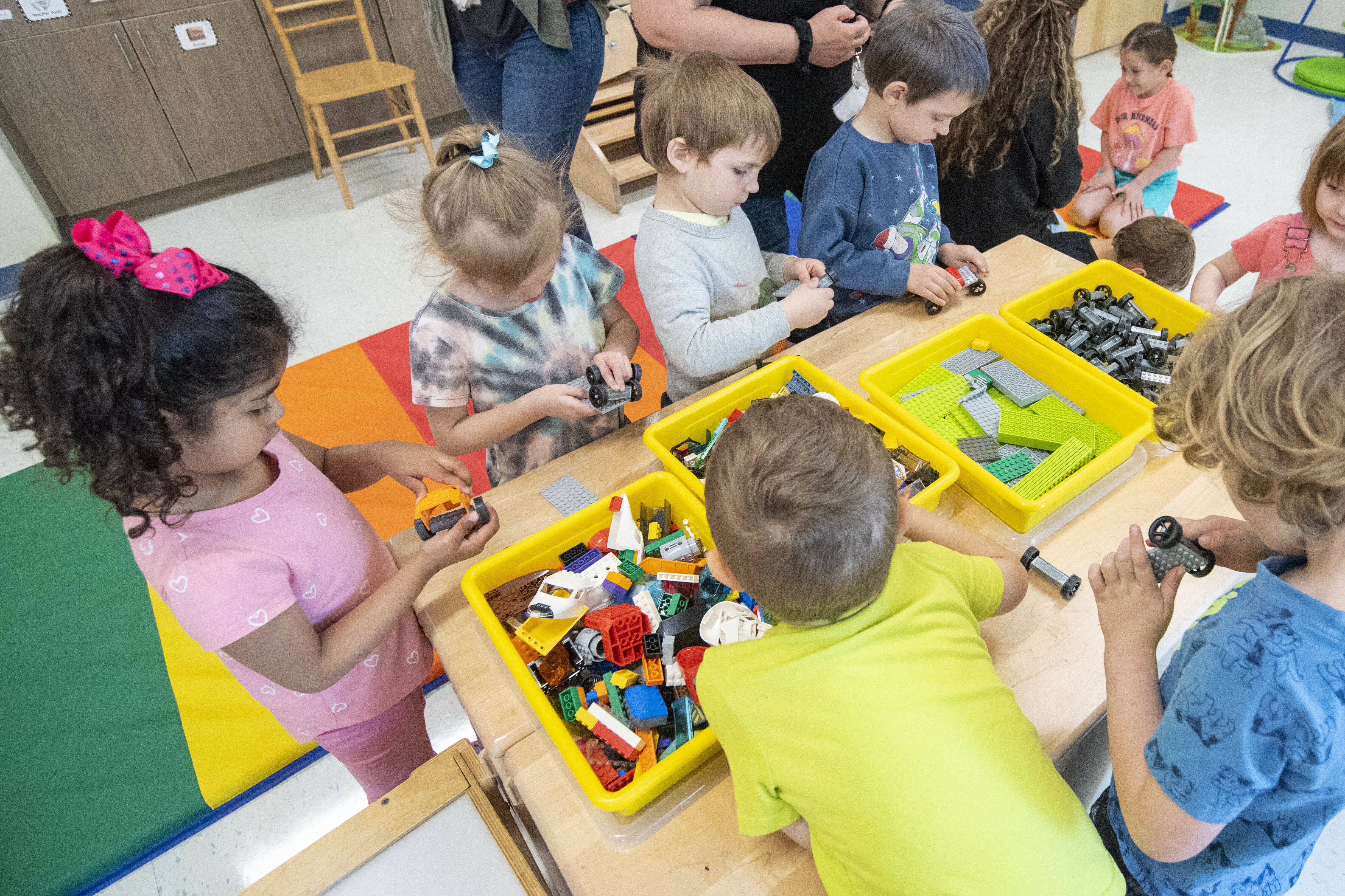 Children playing with toys and building blocks in a classroom setting.