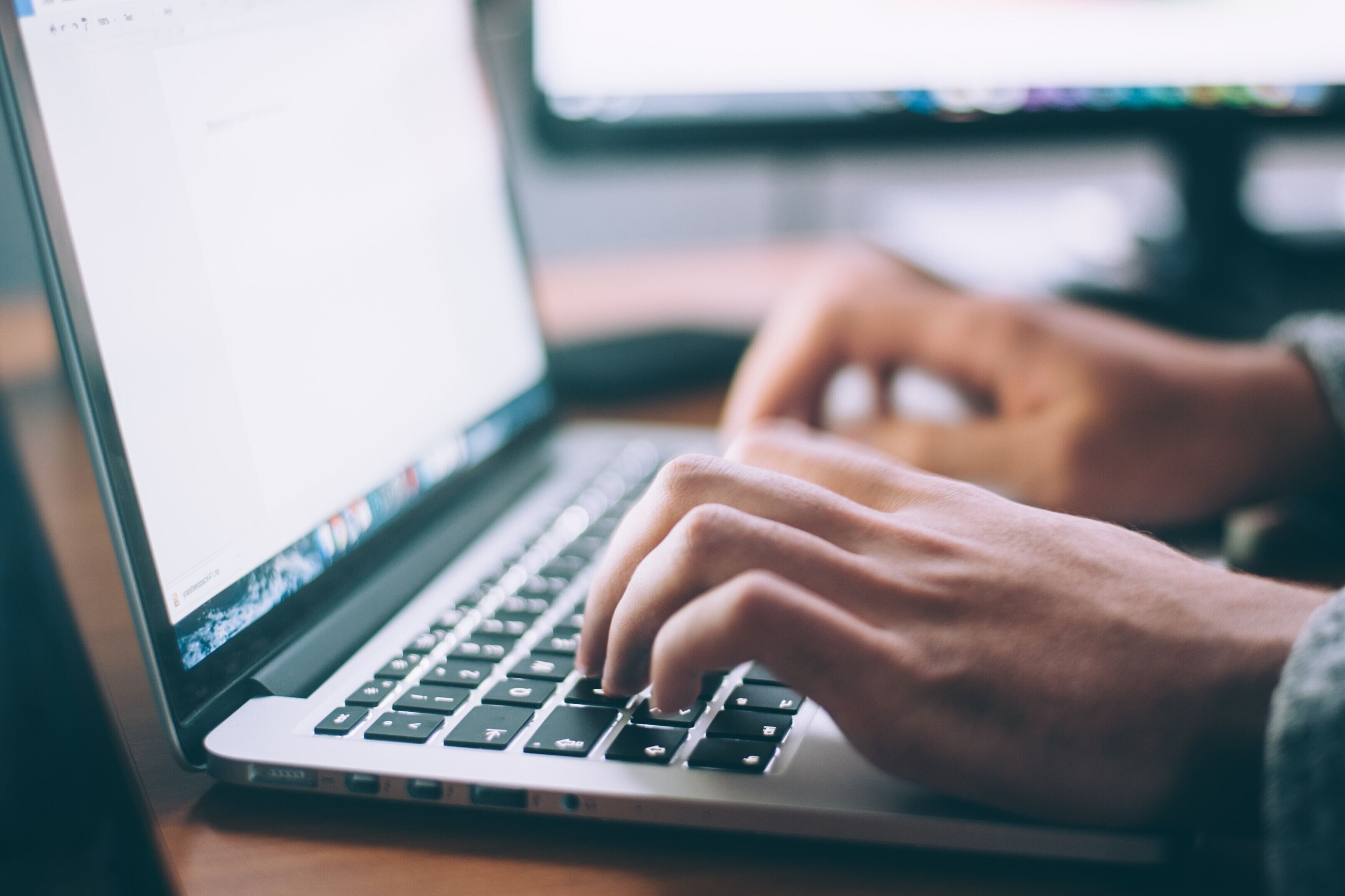 Hands typing on laptop