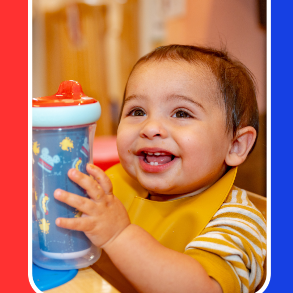 Young child happily holding a cup