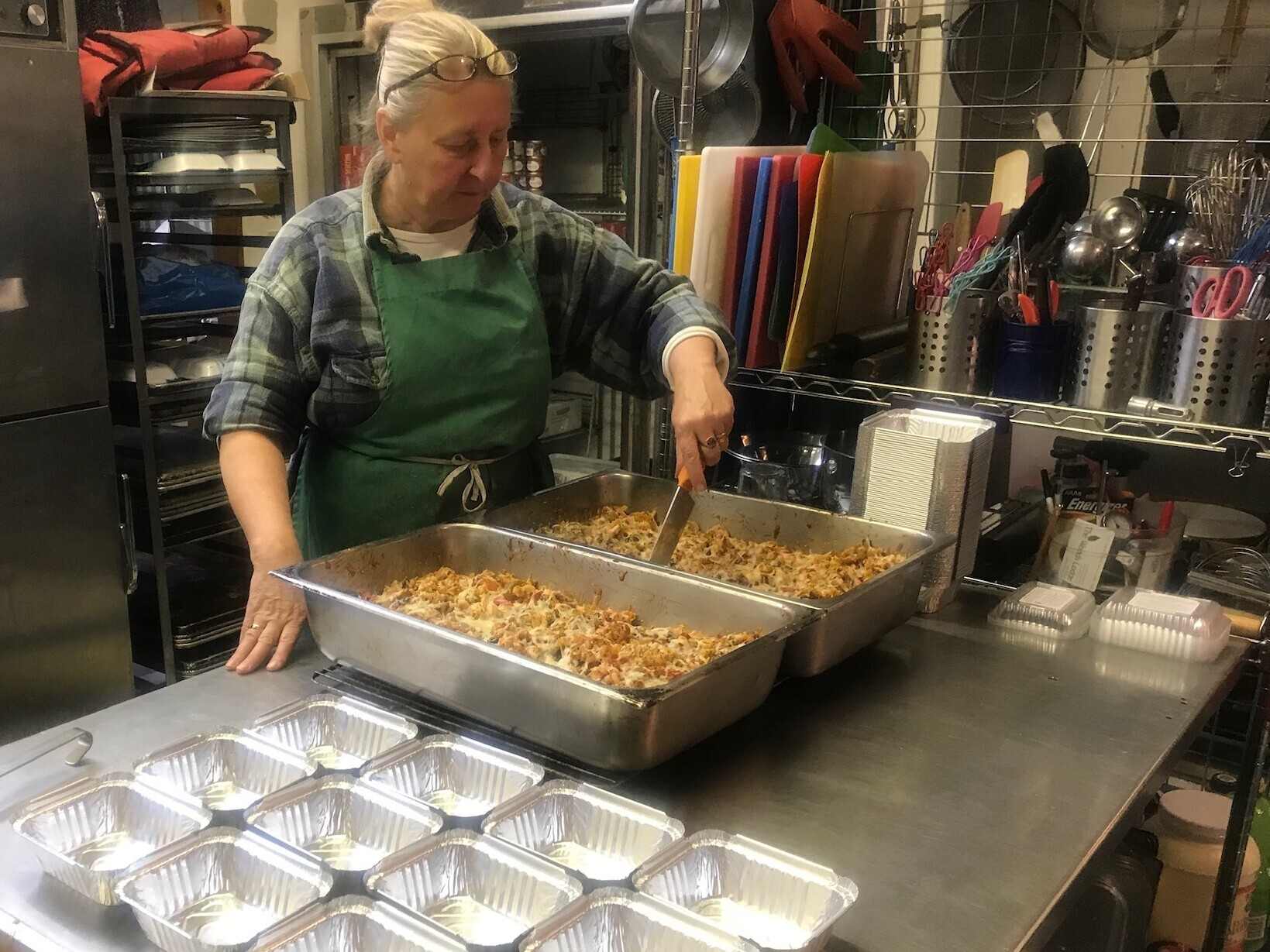 Woman is preparing food to be put into containers for distribution