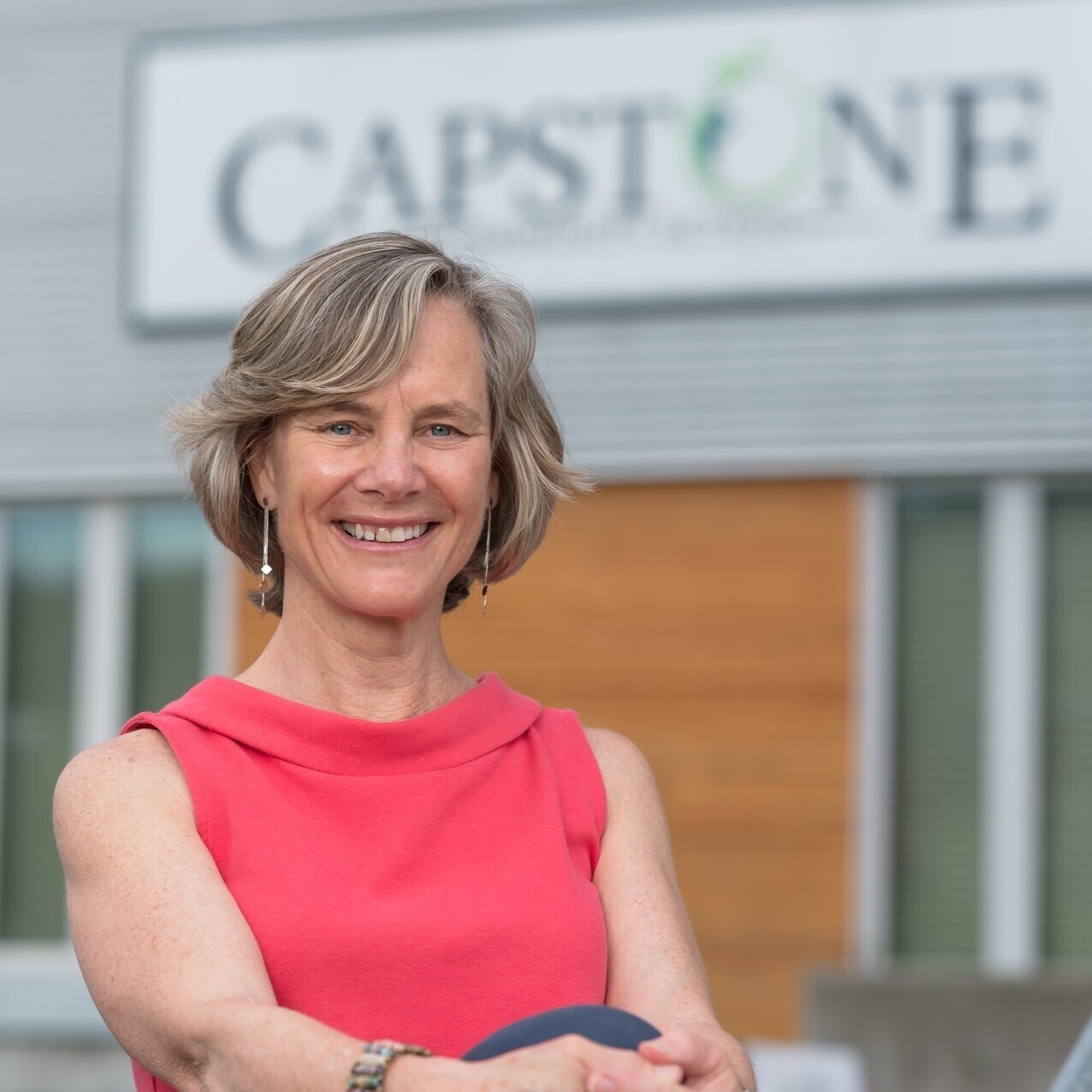 Image of a woman leaning back posed in front of the Capstone sign
