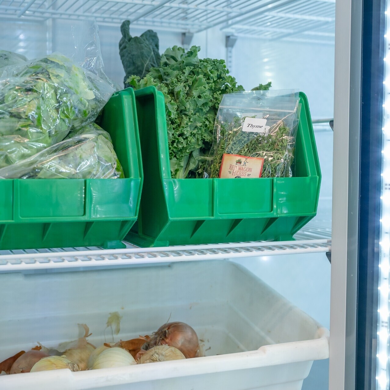 Vegetables in bins in a clear door fridge