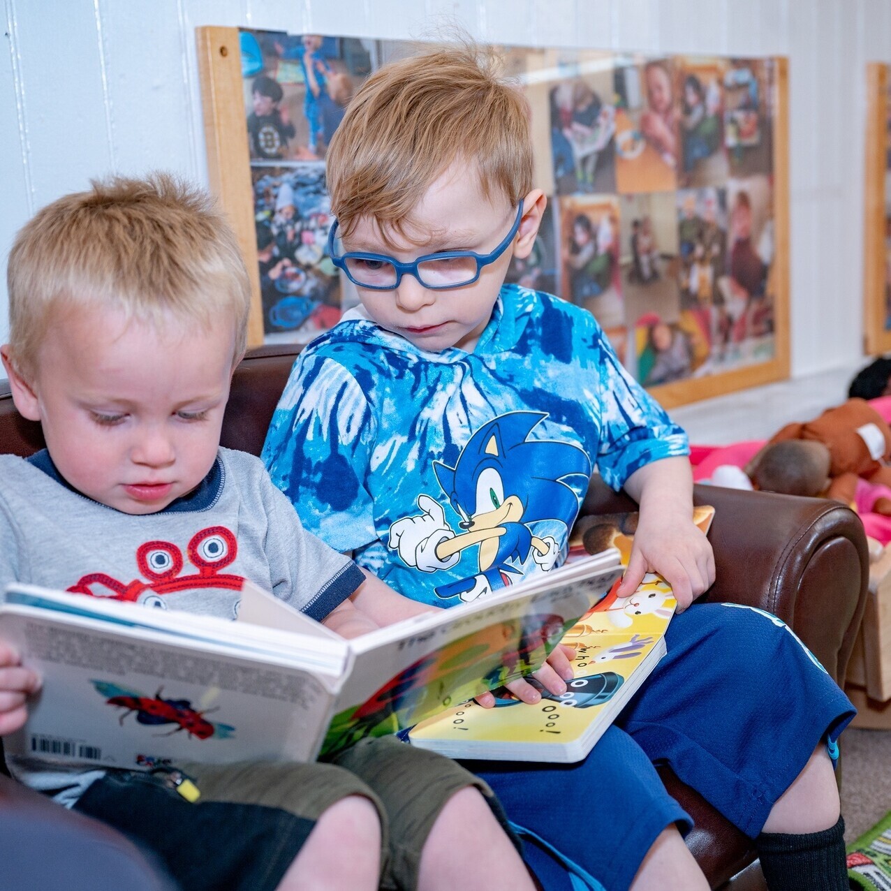 Young children reading books on a small couch