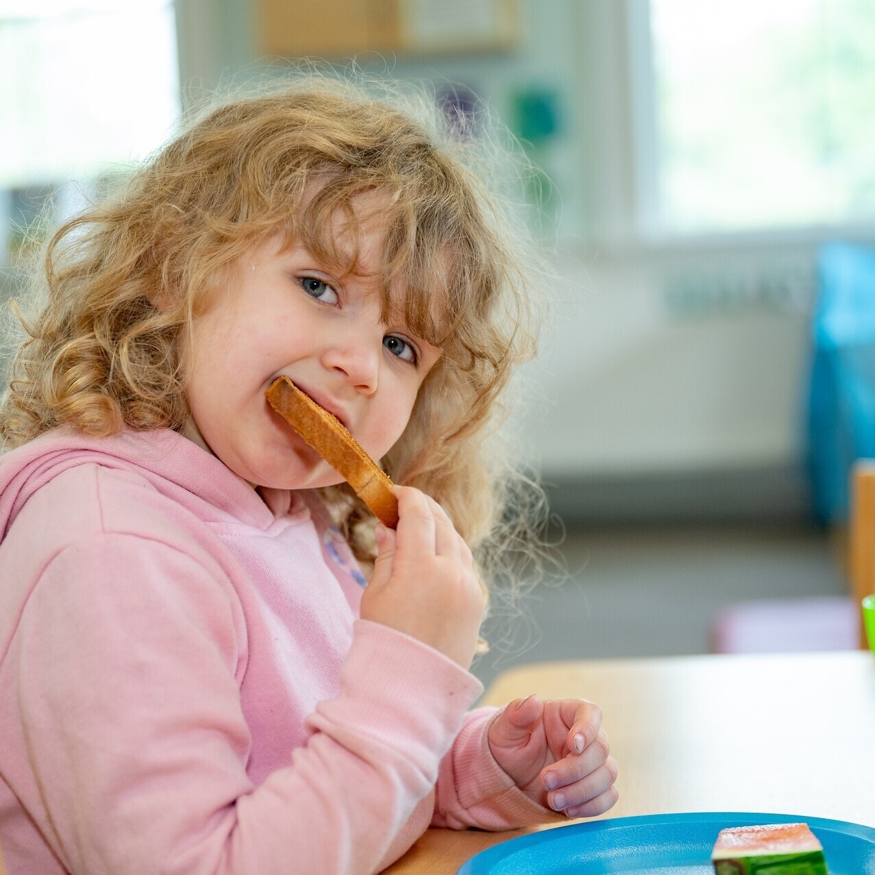 A young girl eating a piece of toast