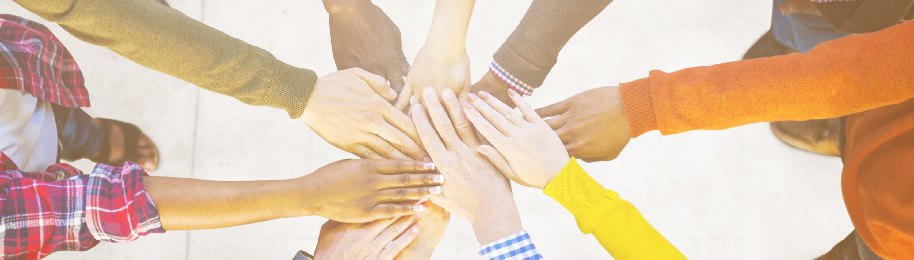 Multiple different people placing a hand on top of one another