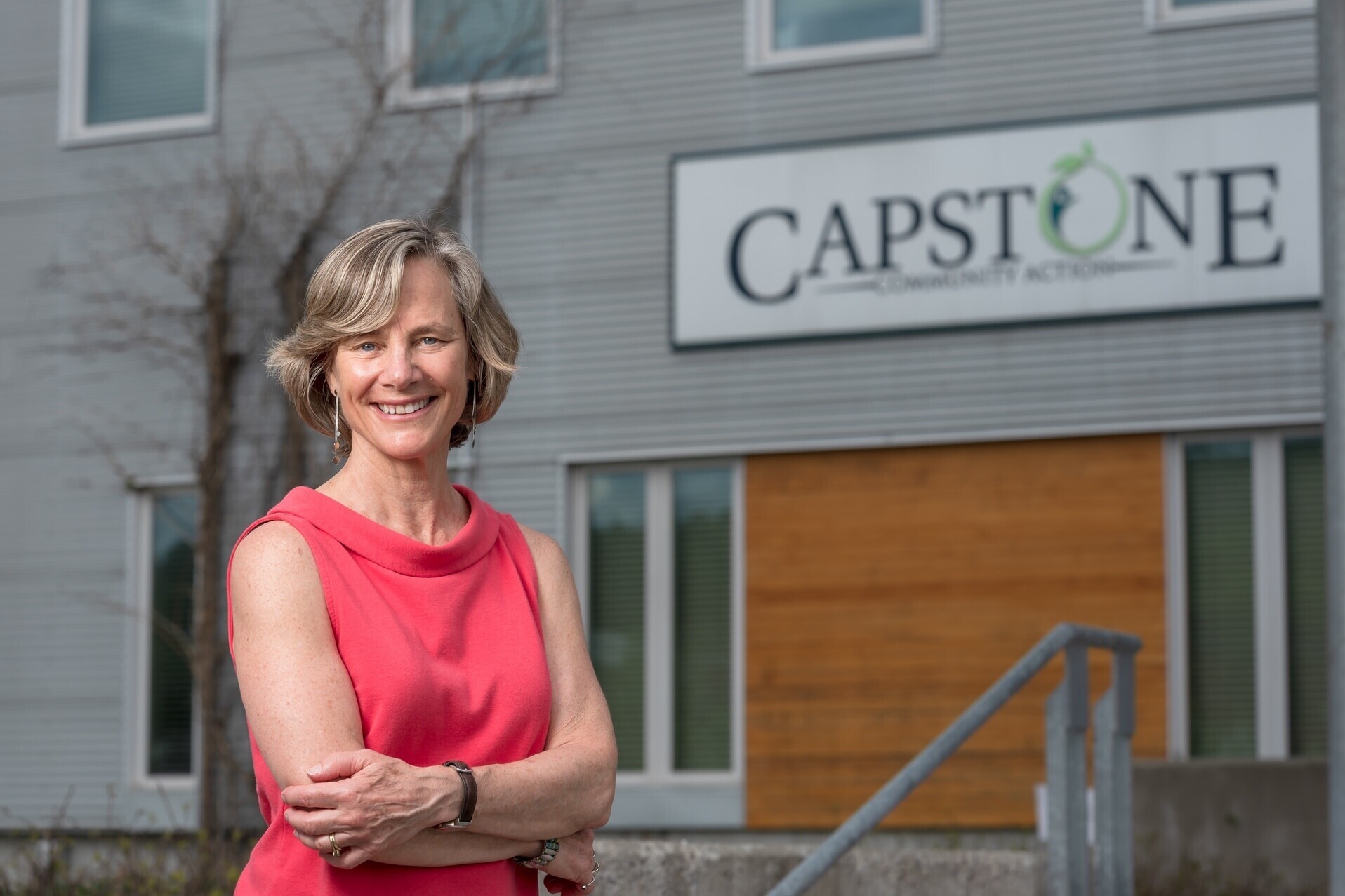 Sue Minter, smiling, poses in front of Capstone office sign